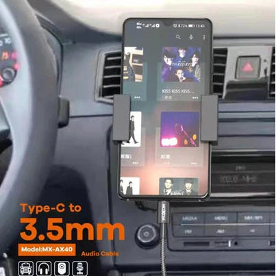 Car dashboard with a phone holder and audio cable, featuring MOXOM branding.